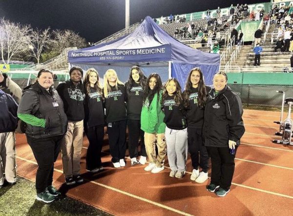 Head Athletic Trainers Ms. Erin (far left) and Ms. Cassidy (far right) smile with the student aide trainers before their last home game of the season against Marist. This was the last playoff game for the Hornets after Marist’s defeat. (Credit: @‌roswellsportsmed on Instagram)

